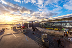 Passenger aircraft parked at an airport gate beside the terminal during sunset