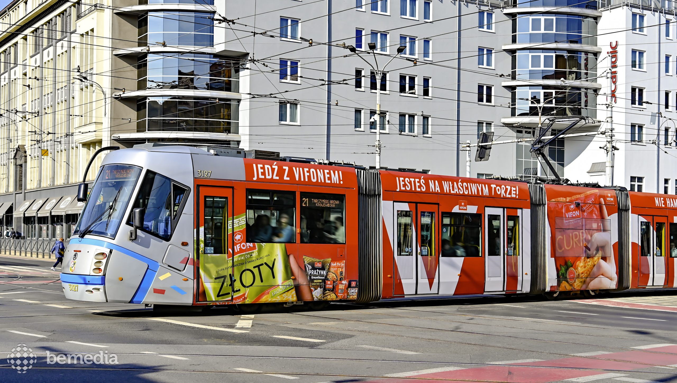 Czerwony jadący tramwaj z reklamą Vifon