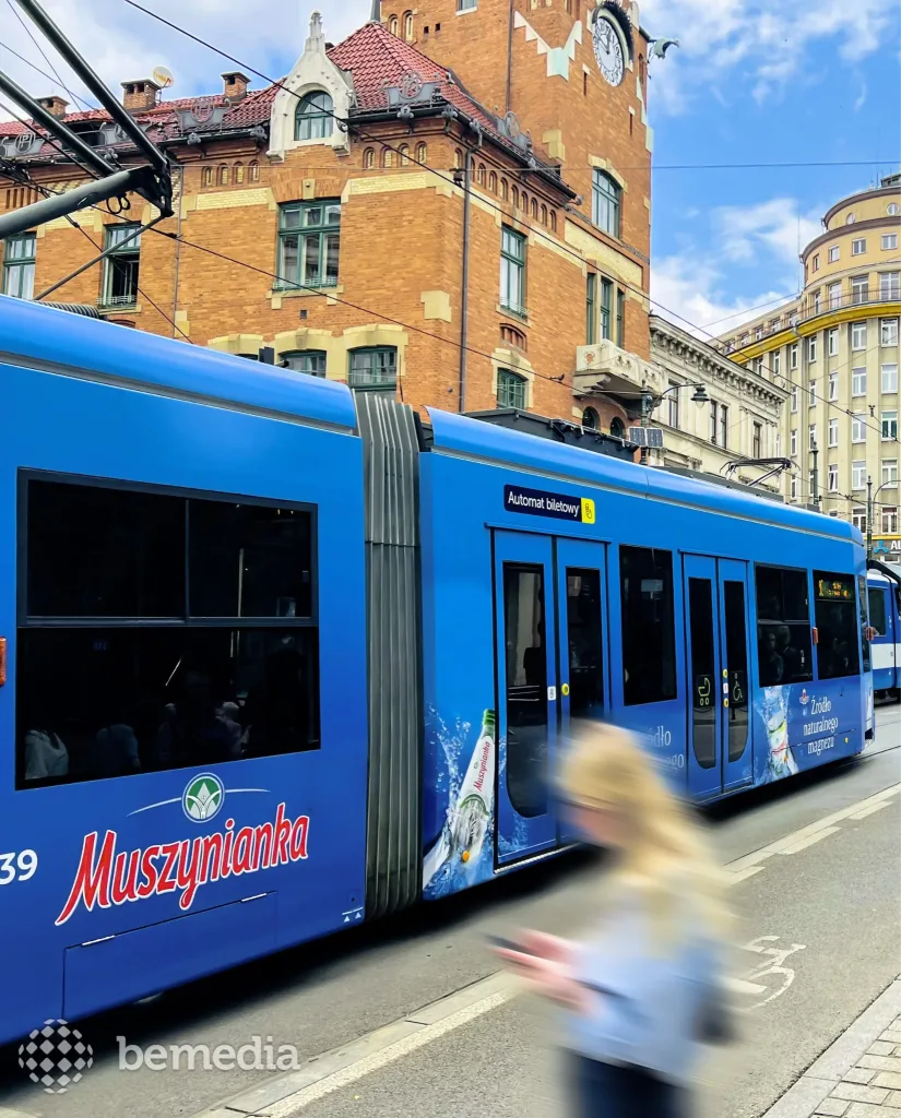 Blue tram with full-body advertising traveling through a city street