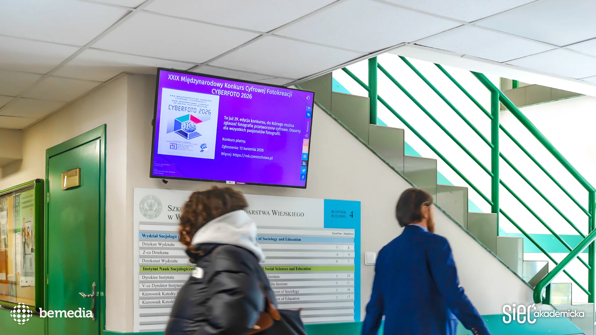 Ekran digital signage na uczelni wyświetlający informacje o konkursie fotograficznym CYBERFOTO 2026.