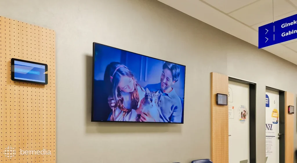 Ekran LCD z reklamą na korytarzu przychodni, obok gabinetów lekarskich